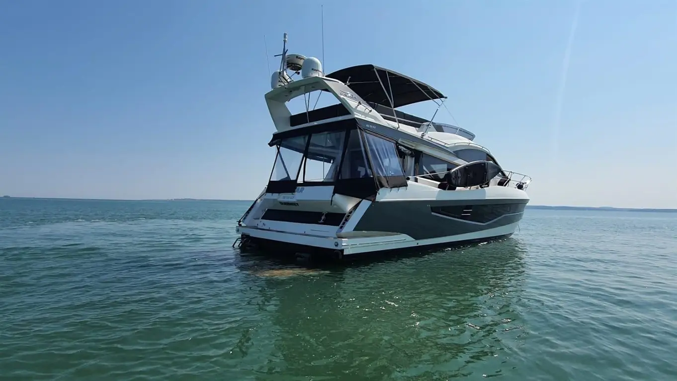 Luxury boat anchored in calm turquoise water under a clear blue sky, showcasing its elegant design and spacious deck.